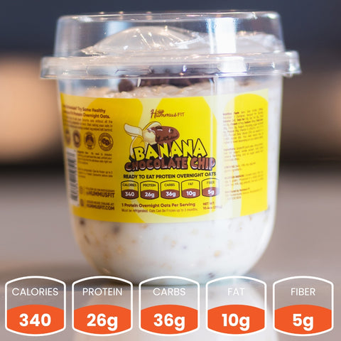A clear cup of Overnight Oats with a yellow label sits on a table—a healthy breakfast with 340 calories, 26g protein, 36g carbs, 10g fat, and 5g fiber per serving. Perfect for meal prep!.