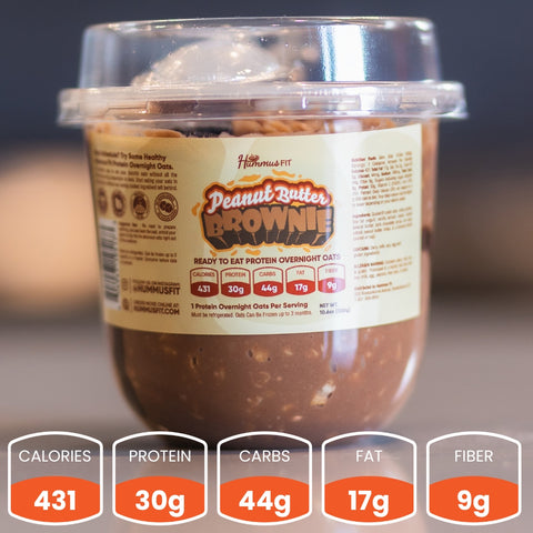 A plastic cup of Overnight Oats (Flavors Vary) - Subscription sits on a table—a tasty, healthy breakfast with 431 calories, 30g protein, 44g carbs, 17g fat, and 9g fiber. The oats look rich and chocolatey.
