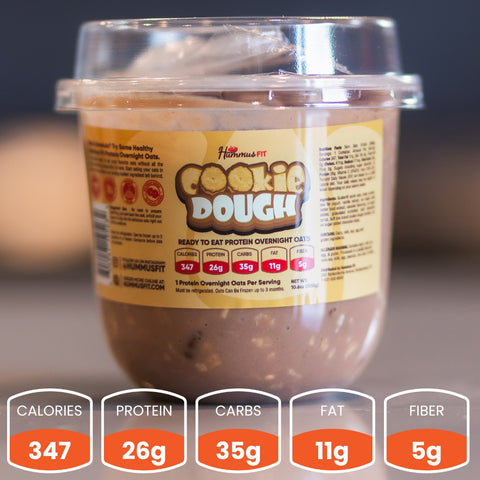 A plastic container of Hummus Fit cookie dough overnight oats with a yellow label. Nutrition info below: 347 calories, 26g protein, 35g carbs, 11g fat, and 5g fiber per serving.