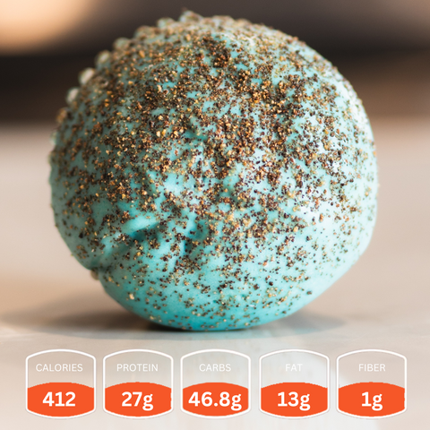 A round, blue Buffin Muffin dusted with dark spices sits on a light surface. Nutrition facts below: 412 calories, 27g protein, 46.8g carbs, 13g fat, and 1g fiber—a nutritious snack in every bite.