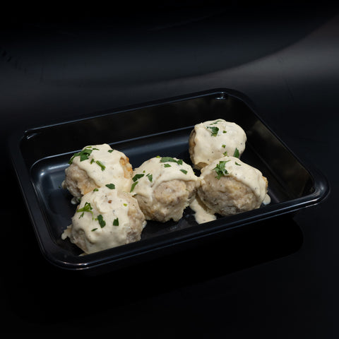 Enjoy Keto Ricotta Meatballs—four round, low carb ground chicken meatballs in creamy white sauce, garnished with herbs and served in a black tray. Perfect for keto diets and elegant low carb meals.