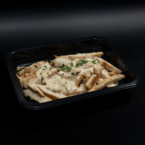 Marry Me Keto Chicken: Sliced grilled keto chicken topped with creamy white sauce and herbs, served in a black rectangular container against a dark background for a protein-packed, low-carb meal.