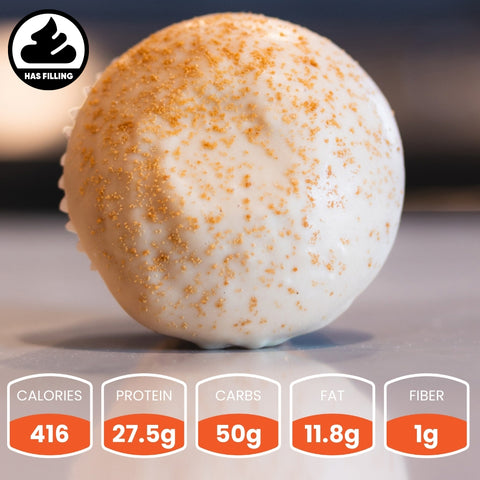 A Buffcoff Buffin Muffin—a round protein snack with golden sprinkles and a filling—sits on a surface. Nutrition: 416 calories, 27.5g protein, 50g carbs, 11.8g fat, 1g fiber. Perfect for a nutritious snack on the go.