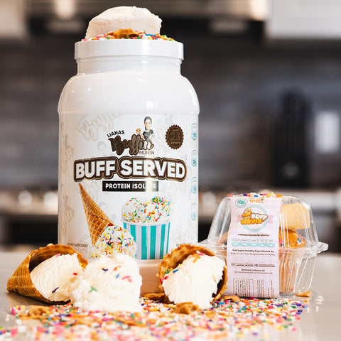 A large container of Buff Served whey protein isolate, vanilla ice cream cones with rainbow sprinkles, and a clear pack of Lianas Buffin Muffin - Protein Isolate sit on a kitchen counter, with sprinkles scattered around.