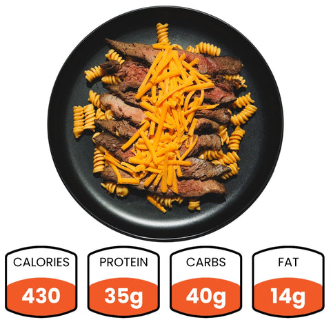 A black plate features Hot Honey Steak & Mac: rotini pasta, grass-fed flank steak slices, and shredded cheddar. Nutrition below: 430 calories, 35g protein, 40g carbs, 14g fat—a high-protein meal prep option.