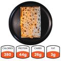 The Spiced Chicken Fold, a rectangular grilled wrap with juicy grilled chicken, is displayed on a black plate from above. Nutrition facts below show: 380 calories, 44g protein, 26g carbs, and 3g fat in orange and white boxes.