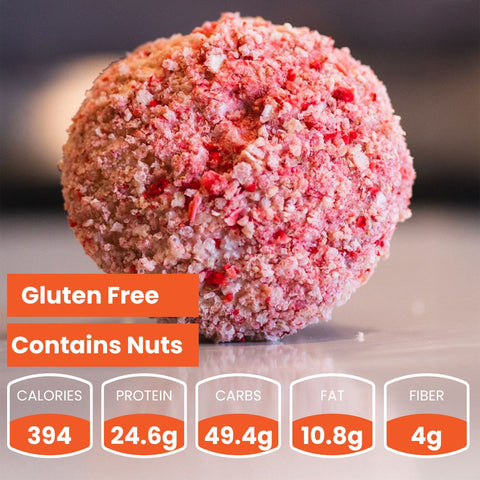 A round, pink crumb-coated Buffin Muffin sits on a surface. Text reads: Gluten Free, Contains Nuts. 394 calories, 24.6g protein, 49.4g carbs, 10.8g fat, 4g fiber—perfect nutritious snack for on-the-go!.