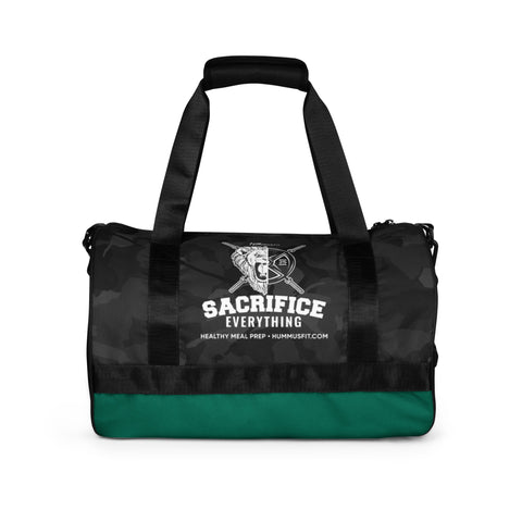 The Hummus Fit Cylinder Black Camo Gym Bag is water-resistant in black and green, featuring “Sacrifice Everything” with a lion and crossed swords logo on the front. Below it reads, “Healthy Meal Prep - Hummusfit.com.”.
