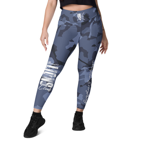 A woman models Blue Camo Leggings With Pockets, featuring a high-waisted fit and white graphic text, paired with black athletic shoes and standing with one leg slightly ahead.