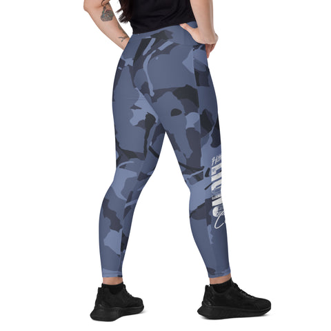 A person with a tattoo on their left arm stands with their back to the camera, wearing Blue Camo Leggings With pockets and black sneakers. A white graphic is visible on the back of the right leg.