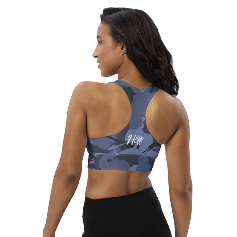 A woman with long dark hair wears the Blue Camo Sports Bra, featuring a white HF logo on the back, paired with black leggings. The compression fabric provides support and comfort for any workout as she stands with her back to the camera.