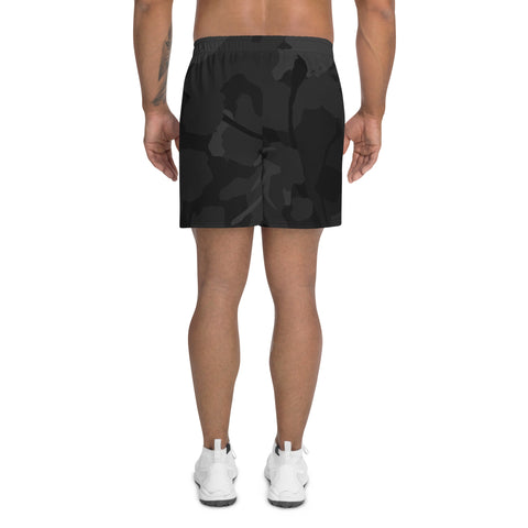 A person, seen from behind with only their lower body visible, is wearing Mens Athletic Long Shorts in black and gray camouflage and white sneakers, with no shirt. The shorts are water-repellent.