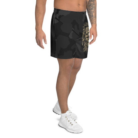 A man models Mens Athletic Long Shorts, featuring a black water-repellent fabric and gold lion design on the side, paired with white athletic shoes and showcasing a left arm tattoo, set against a plain white background.