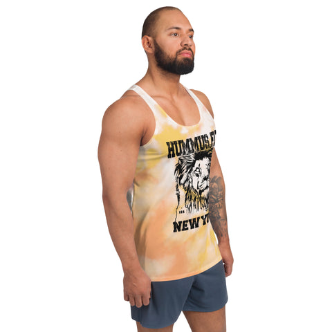 A man with a beard and tattooed arm wears the Pink & Gold Tank Top featuring vibrant tie-dye colors, a lion graphic, and HUMMUS FIT NEW YORK text, paired with blue shorts, standing against a plain white background.