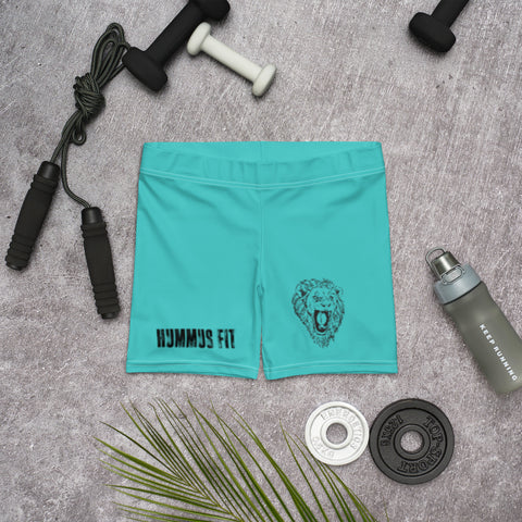 Womens Turquoise Shorts feature a lion graphic and HUMMUS FIT text with a comfy elastic waistband. Displayed on gray, theyre surrounded by gym essentials like a jump rope, dumbbells, water bottle, weight plates, and a palm leaf.