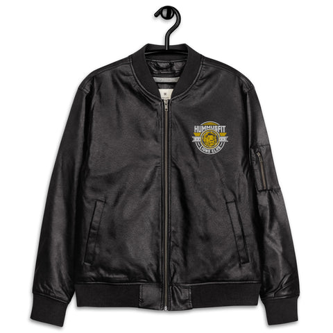 The Lions Club Leather Bomber Jacket, shown in black on a hanger, features ribbed cuffs, a front zipper, and a chest patch that reads HUMMUSFIT ATHLETIC CLUB with a gold emblem.