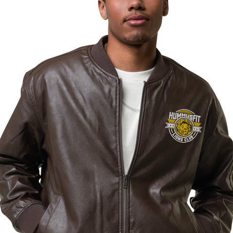 A person wears the Lions Club Leather Bomber Jacket featuring a Hummusfit Lions Club patch on the chest, over a white shirt. Their face is partially out of frame.