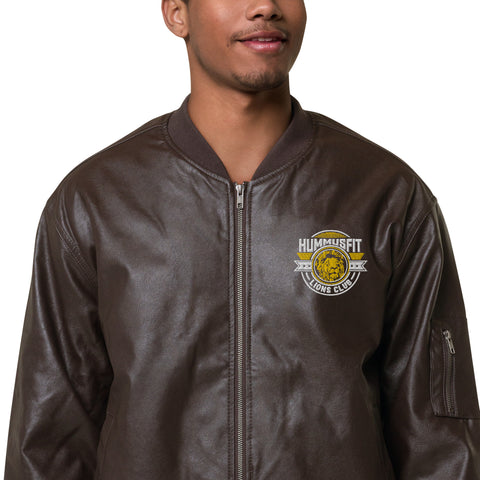 A person wearing the Lions Club Leather Bomber Jacket in brown PU leather with a yellow and white Hummusfit Lions Club logo on the left chest, standing against a white background. This stylish piece features classic branding.