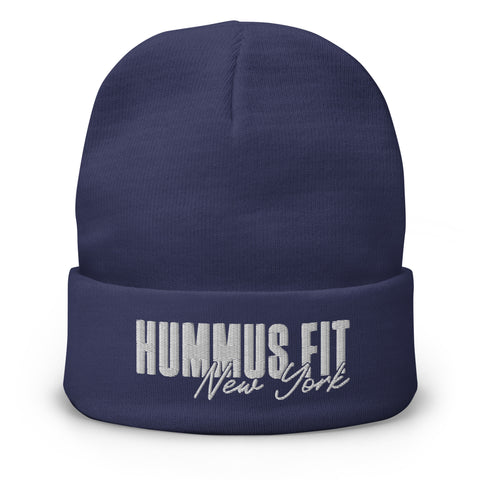 The Hummus Fit NY Embroidered Beanie is a navy blue cotton blend beanie featuring HUMMUS FIT New York boldly embroidered in white on the front fold.