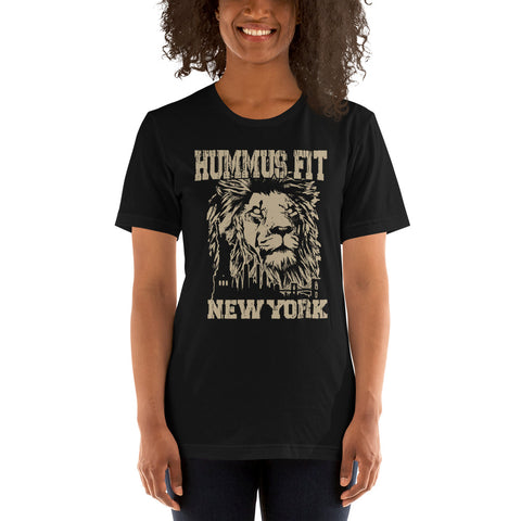 A smiling person wears the Unisex Hummus Fit New York Black T-Shirt, a lightweight, 100% cotton top with a graphic lion’s face and “HUMMUS.FIT NEW YORK” in large, bold, distressed beige letters.