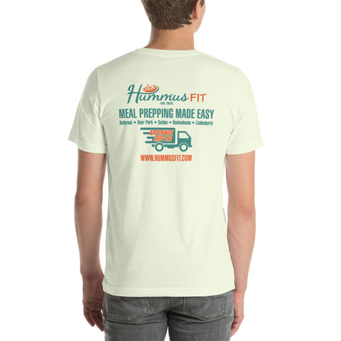 A person wears the Unisex Hummus Fit New York Citron T-Shirt—100% cotton, white, with colorful branding, a food truck graphic, and www.hummusfit.com on the back, promoting meal prep services.