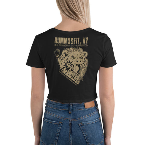 A woman models the Women’s Crop Tee—a black, slim fit with a gold roaring lion holding a spatula and whisk on the back, featuring “HJMMJSTEL, NY Meal Prepping Made Easy - HJMMJSTEL.COM.”.