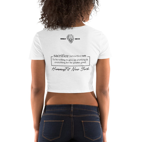 A woman with curly hair wears the Women’s Crop Tee, a slim fit white top. Its back showcases text defining sacrifice: being willing to give up anything & everything for the greater good. Hummingbird New York.