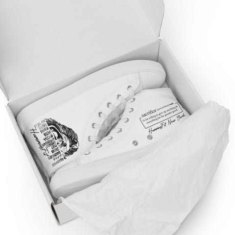 A pair of Women’s high top canvas shoes in white are displayed in an open shoebox. One sneaker shows black printed text and a portrait on the outer side, while tissue paper partly covers its breathable lining.