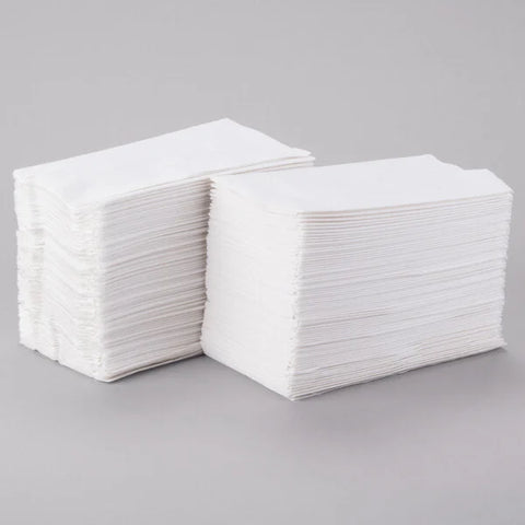 Two neat stacks of white, rectangular 15"x17" Dinner Napkins are placed side by side on a light gray surface—perfect for bulk use and available in a convenient 150pcs bag.