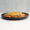The FitWendy Double Stack Bowl features baked sweet-potato fries topped with high-protein ground beef, melted cheddar cheese, and diced red onions, all served in a black bowl on a white marble surface.