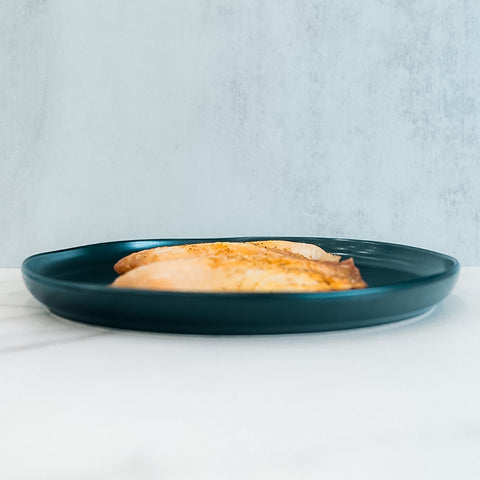Baked Herbed Tilapia 1lb Competition Approved is served on a dark teal plate, set against a light background—perfect for meal prep and supporting weight loss goals.