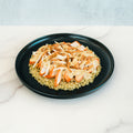 A Brookfield Chicken Bowl featuring sliced grilled chicken breast on a bed of rice, topped with sautéed onions and garnished with crispy fried onions, served on a black plate over a white marble surface—perfect for easy meal prep or a tasty weeknight dinner.