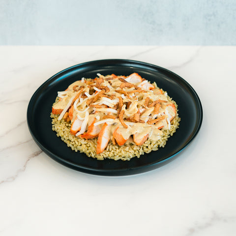 A Brookfield Chicken Bowl featuring sliced grilled chicken breast on a bed of rice, topped with sautéed onions and garnished with crispy fried onions, served on a black plate over a white marble surface—perfect for easy meal prep or a tasty weeknight dinner.