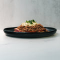 A black plate holds a Street Corn Beef Bowl—ground beef topped with creamy sauce and herbs—on a light backdrop, ideal for high-protein meal prep and macro-friendly diets.