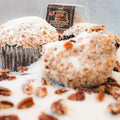 Close-up of two Buffin Muffin - German Chocolate Cake high-protein muffins, topped with shredded coconut and pecans, with the package in the background for a fitness-friendly treat.