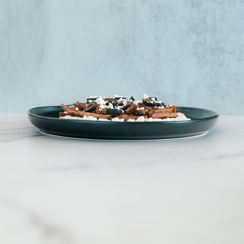 An Olympian Chicken Gyro Bowl featuring a shallow bowl filled with high-protein chicken gyro slices, black olive rounds, and crumbled white cheese.