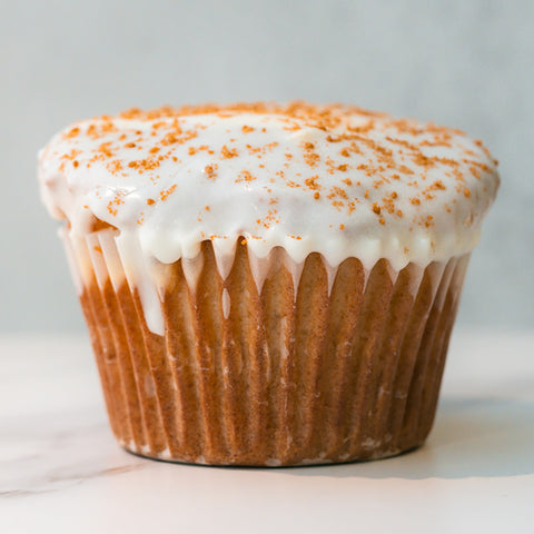 The VIP Buffin Muffin - Cookie Butter Tres Leches features white icing drizzled down the sides and a light sprinkle of cookie butter crumbs, displayed on a white surface against a neutral background.