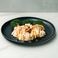 Five Chicken Mushroom Pot Stickers drizzled with teriyaki sauce are arranged on a black plate, with mushrooms and broccoli florets in the background, set on a white marble surface.