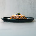 A black plate holds a Honey Garlic Beef Bowl with rice, ground beef, shredded cheese, and black olives on a light gray background.