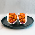 Enjoy the Honey Garlic Crispy Chicken Tacos—two soft taco shells filled with seasoned, golden-brown crispy chicken and shredded purple cabbage, served on a black plate against a light background. This irresistible taco delivers the perfect fusion of honey garlic flavor and classic crunch, making it an ideal high-protein meal option for your next food prep session.