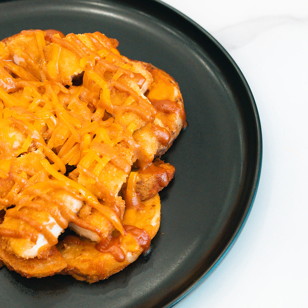 A close-up of the Closed on Sunday Crispy Chicken Bowl, served on a black plate with a white marble background—a high-protein, macro-friendly lunch option for those seeking a delicious meal.