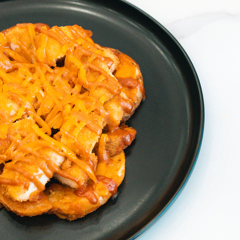 The "Closed on Sunday" Crispy Chicken Bowl features crispy chicken and melted shredded cheddar cheese on a golden waffle, served on a black plate—ideal for a macro-friendly lunch or a high-protein meal.