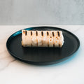 The Golden Arches Mac Daddy Wrap, a grilled cheeseburger-inspired burrito with char marks, sits on a black plate over white marble—perfect for a delicious, macro-friendly lunch against a light background.
