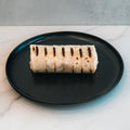 “The Golden Arches” Mac Daddy Wrap, a high-protein meal prep option with cheeseburger-inspired flavor and visible char marks, sits on a black plate atop white marble—perfect for a macro-friendly lunch.