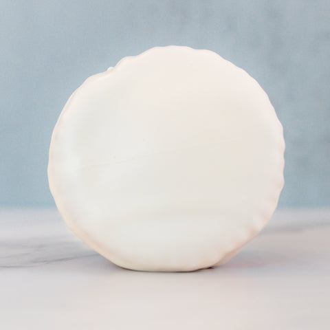 The Red, White Blue Buffin Muffin, a high-protein treat coated in smooth white chocolate, stands upright on light marble with a soft blue background.