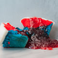 A Red, White Blue Buffin Muffin is split open, showing thick dark purple jam oozing onto a white surface.