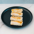 Four pieces of Competition Approved Oven Baked Cod 1lb arranged on a round black plate atop white marble—ideal for high-protein meal prep.