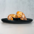 The Breakfast Burrito, filled with eggs, cheese, and turkey bacon and cut in half, is served on a black plate with dipping sauce against a light background.