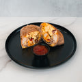 The Breakfast Burrito, packed with eggs, cheese, veggies, and turkey bacon, is sliced in half and served on a black plate with salsa—an ideal high-protein meal prep option.