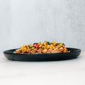 The Southwest Chicken Bowl features diced grilled chicken topped with corn, chopped tomatoes, and fresh herbs, all served in a black bowl on a white surface against a light gray background.